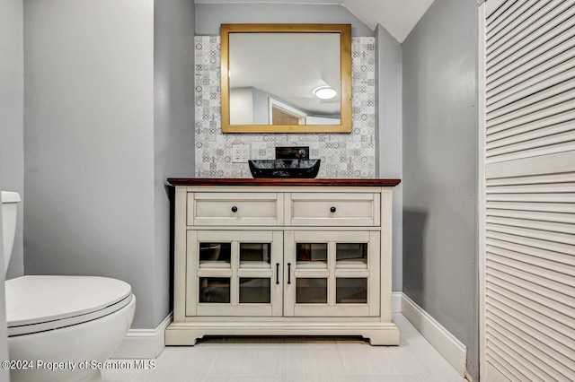 bathroom with vanity, lofted ceiling, and toilet