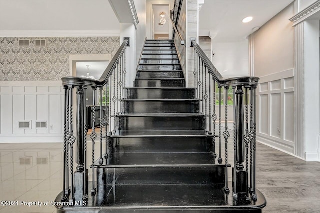 stairs with a notable chandelier, wood-type flooring, and ornamental molding