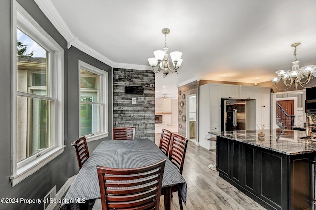 dining space with a chandelier, light wood-type flooring, and crown molding