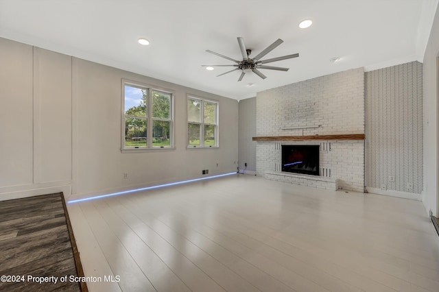 unfurnished living room with ceiling fan, a fireplace, hardwood / wood-style floors, and ornamental molding