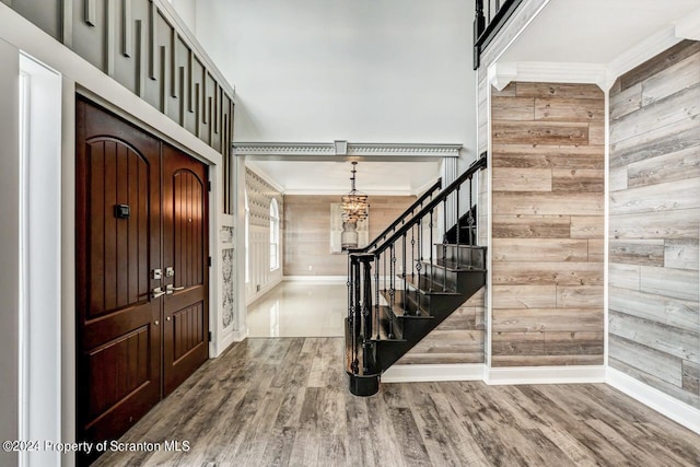 foyer featuring a chandelier, hardwood / wood-style floors, crown molding, and wood walls