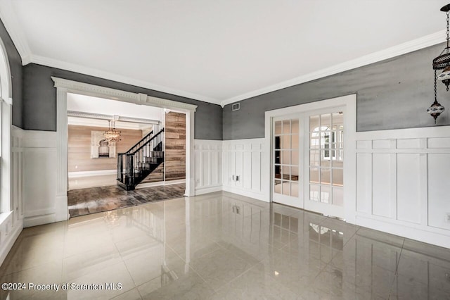 unfurnished room featuring a notable chandelier, ornamental molding, and french doors