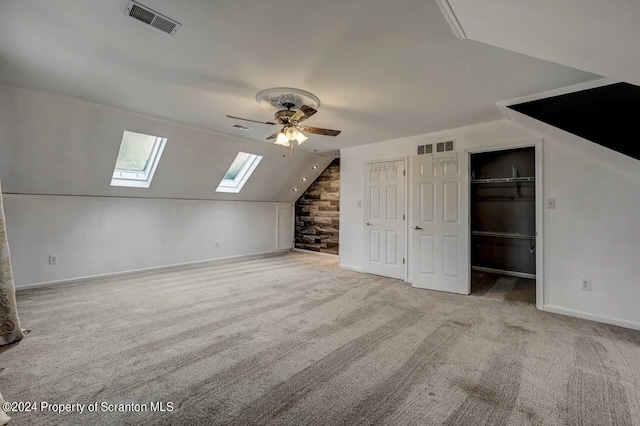 bonus room with light colored carpet, ceiling fan, and vaulted ceiling with skylight