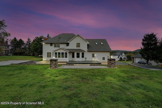 back house at dusk with a yard and a patio