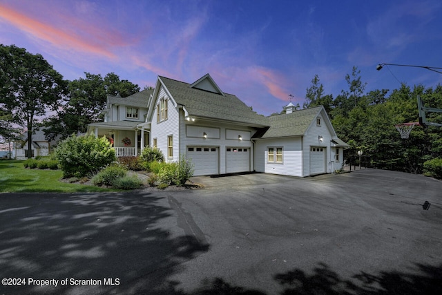 property exterior at dusk featuring a porch and a garage