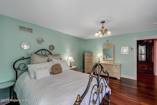 bedroom with a notable chandelier and dark hardwood / wood-style floors