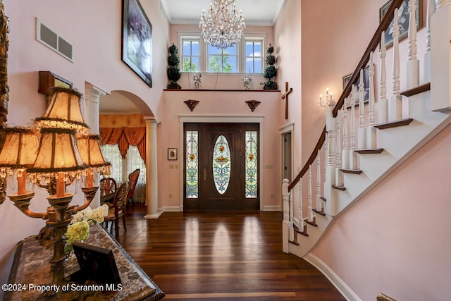 entrance foyer featuring a high ceiling, an inviting chandelier, dark hardwood / wood-style flooring, decorative columns, and crown molding