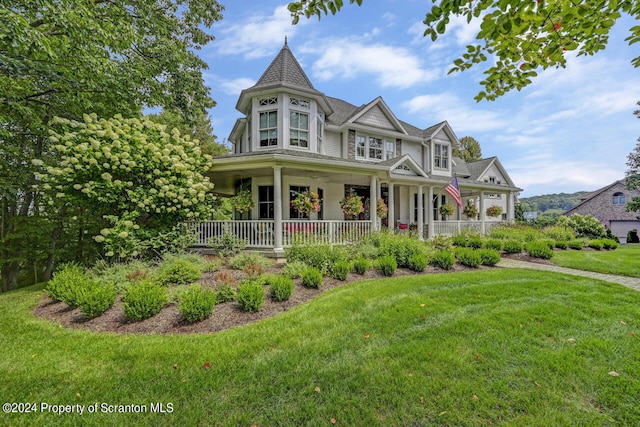 victorian-style house featuring a porch and a front lawn