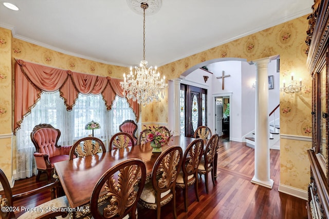 dining space featuring a chandelier, ornamental molding, ornate columns, and dark wood-type flooring