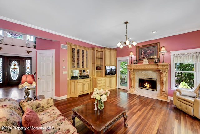 living room with crown molding, dark hardwood / wood-style flooring, a high end fireplace, and a notable chandelier