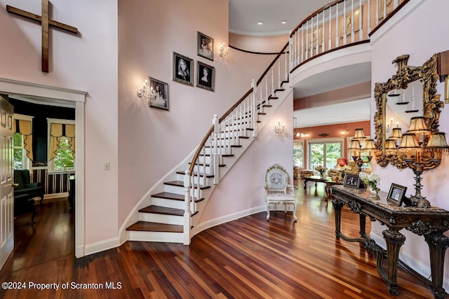 stairway with a towering ceiling, a notable chandelier, and hardwood / wood-style flooring