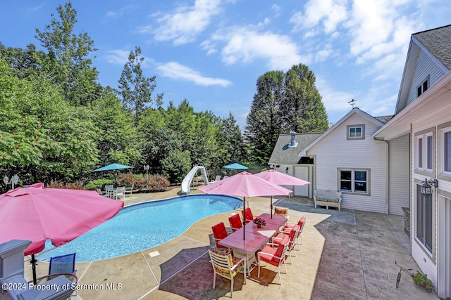 view of pool with a water slide and a patio