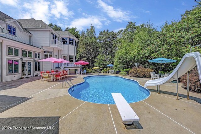 view of swimming pool featuring a diving board, a patio area, and a water slide