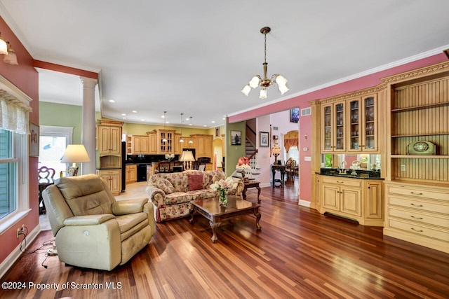 living room featuring a notable chandelier, dark hardwood / wood-style flooring, ornamental molding, and decorative columns