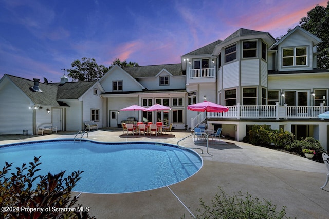 pool at dusk with a patio area