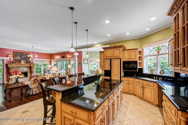 kitchen featuring a center island, black appliances, a kitchen breakfast bar, sink, and decorative light fixtures