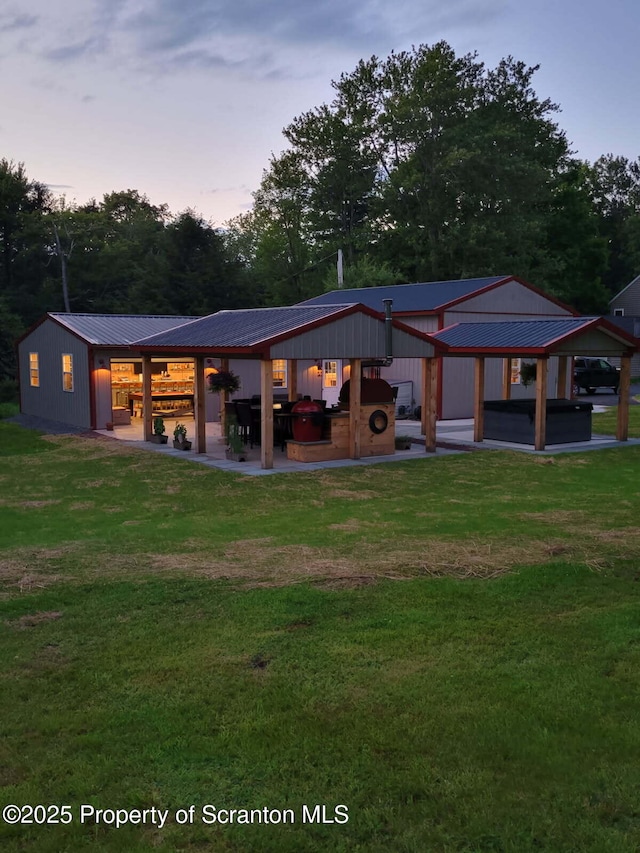144 Crosstown Hwy, Union Dale, PA 18470 - back of property at dusk with a metal roof, a lawn, a patio, and view of wooded area
