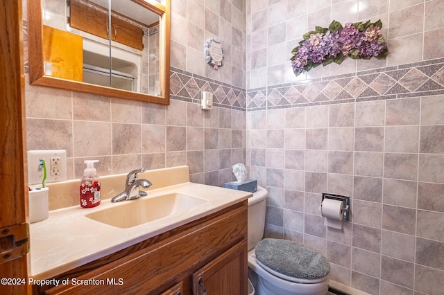 bathroom with vanity, toilet, and tile walls