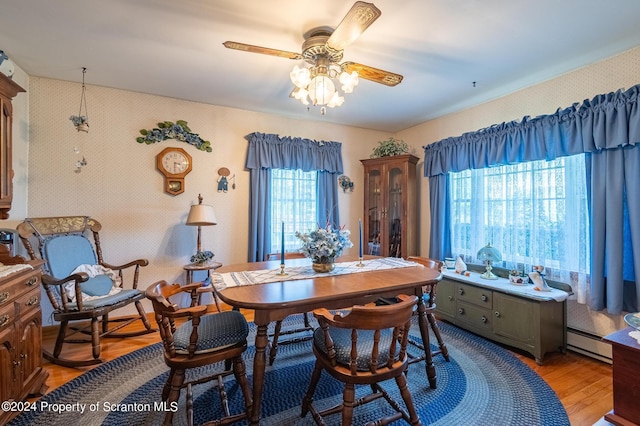 dining area with ceiling fan, baseboard heating, and light hardwood / wood-style flooring