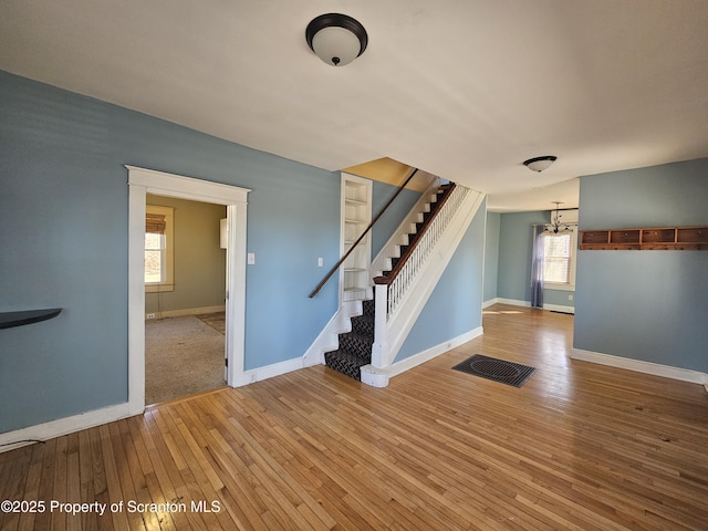 interior space with stairway, wood-type flooring, baseboards, and visible vents