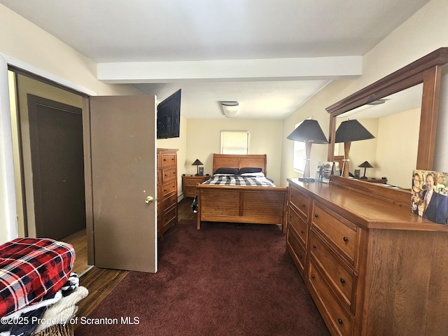 bedroom featuring beamed ceiling and dark carpet