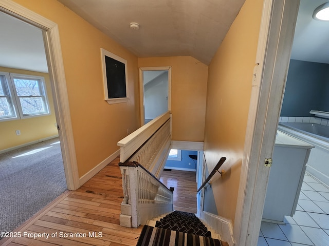 stairs featuring baseboards, wood finished floors, and vaulted ceiling