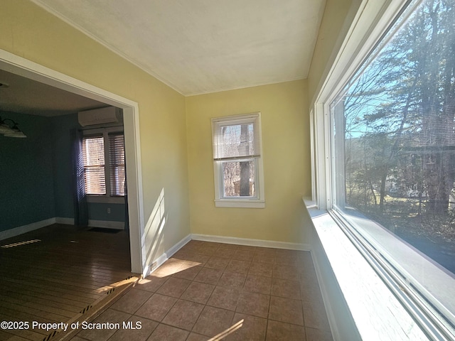 empty room featuring a wealth of natural light, baseboards, and a wall mounted AC