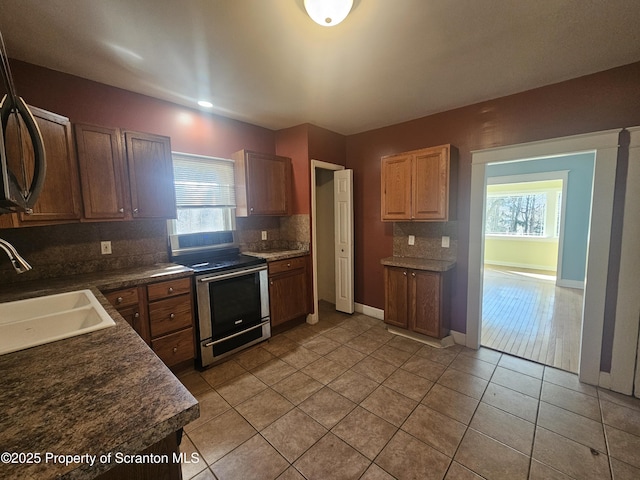 kitchen with backsplash, a healthy amount of sunlight, stainless steel range with electric cooktop, and a sink