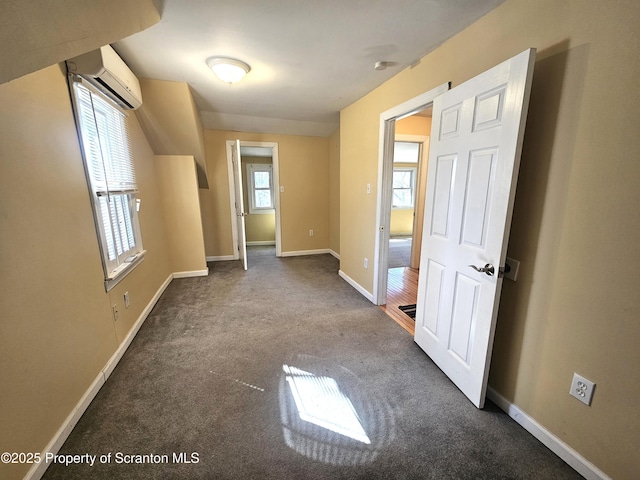 unfurnished room with baseboards, an AC wall unit, and carpet flooring