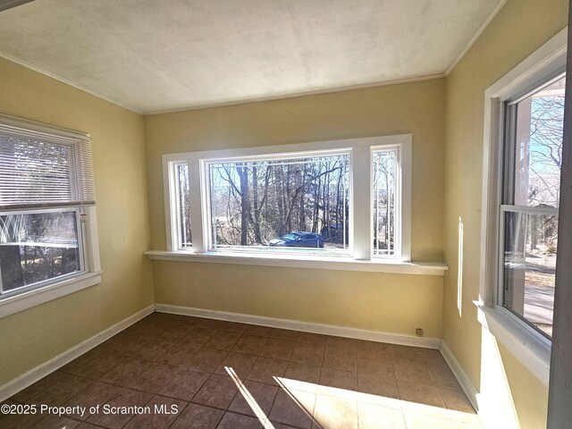 unfurnished room with crown molding, baseboards, and dark tile patterned flooring