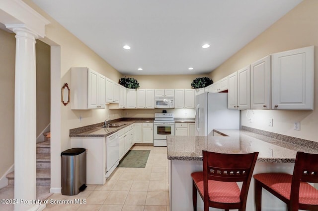 kitchen with white appliances, white cabinets, a kitchen breakfast bar, sink, and kitchen peninsula