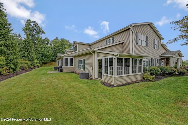 rear view of property with a sunroom and a yard