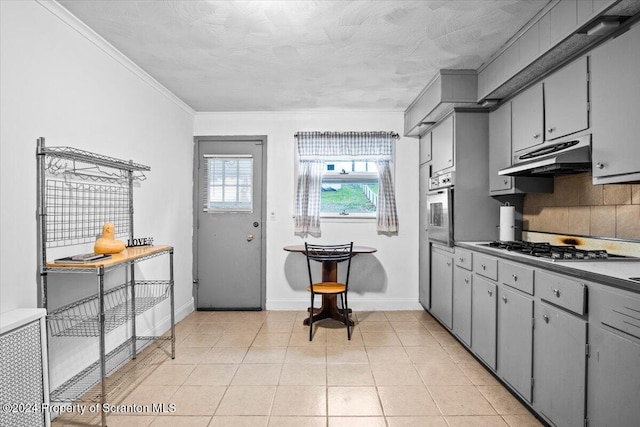 kitchen with gray cabinetry, stainless steel appliances, a textured ceiling, decorative backsplash, and light tile patterned floors