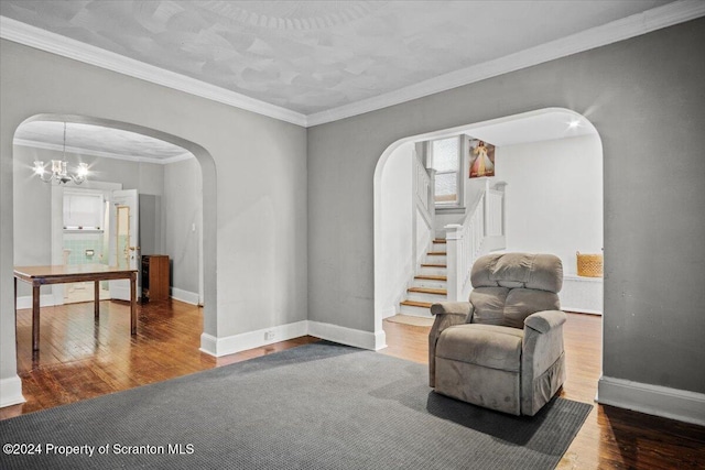 sitting room with hardwood / wood-style flooring, ornamental molding, and an inviting chandelier