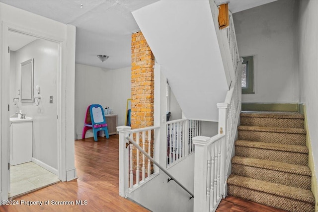 stairs with hardwood / wood-style floors and sink