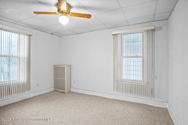 carpeted spare room with a paneled ceiling, ceiling fan, and a wealth of natural light