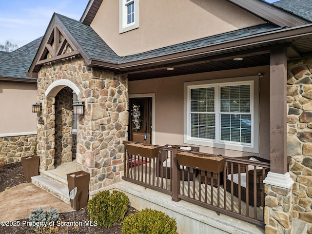 property entrance with stone siding, roof with shingles, covered porch, and stucco siding