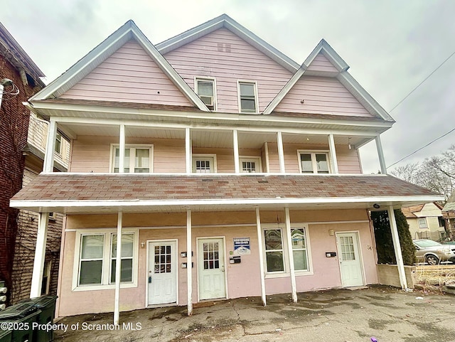 view of property featuring covered porch and roof with shingles