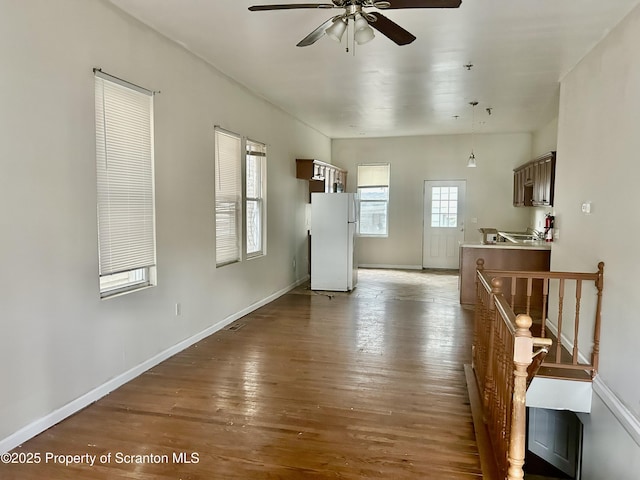 living area featuring ceiling fan, baseboards, and wood finished floors