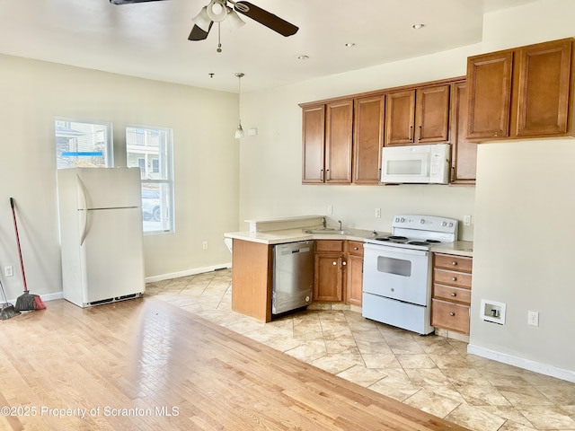 kitchen featuring white appliances, light countertops, and brown cabinets