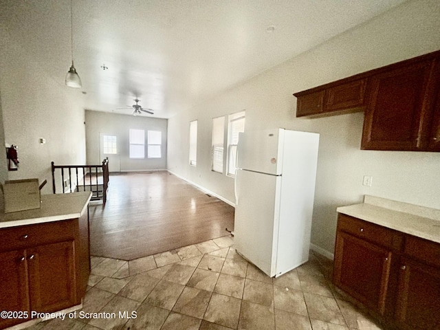 kitchen featuring baseboards, pendant lighting, light countertops, freestanding refrigerator, and a ceiling fan