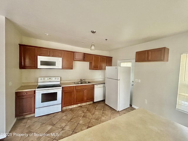 kitchen with white appliances, brown cabinetry, light countertops, and a sink