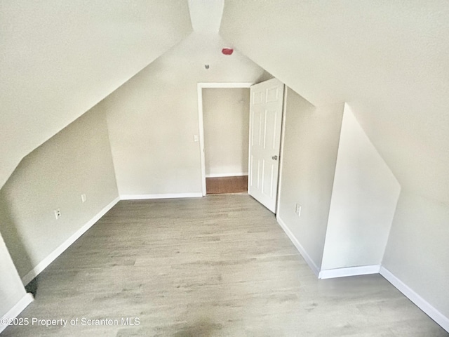 bonus room with baseboards, lofted ceiling, and wood finished floors