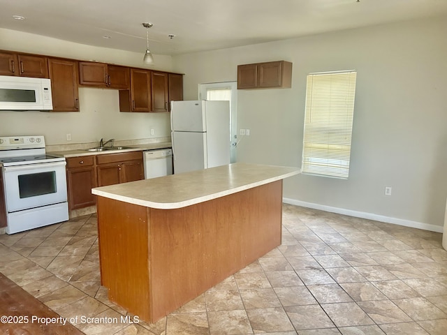 kitchen featuring a sink, a center island, white appliances, light countertops, and baseboards