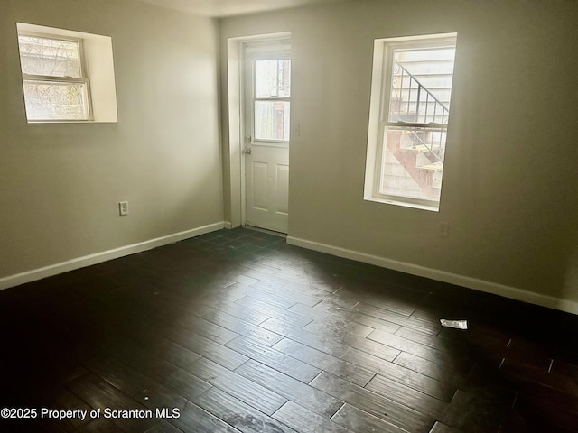 empty room with baseboards and dark wood-style flooring