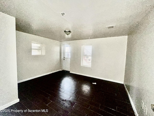 empty room with visible vents, baseboards, and hardwood / wood-style floors