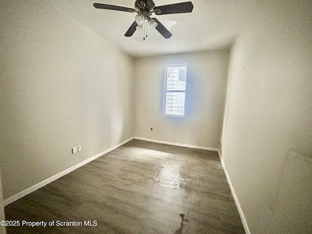 empty room with baseboards, ceiling fan, and dark wood-style flooring