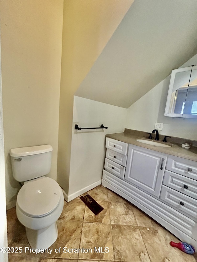 bathroom featuring baseboards, toilet, vanity, and lofted ceiling