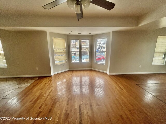 unfurnished room featuring a ceiling fan, baseboards, and wood finished floors