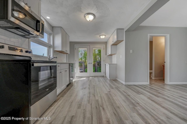 kitchen featuring french doors, light countertops, baseboards, light wood-style floors, and stainless steel appliances